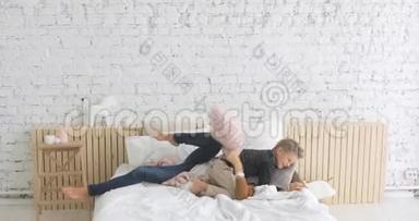 一家人的母亲和儿子在床上玩着有趣的枕头<strong>大战</strong>，躺在床上拥抱在一起。